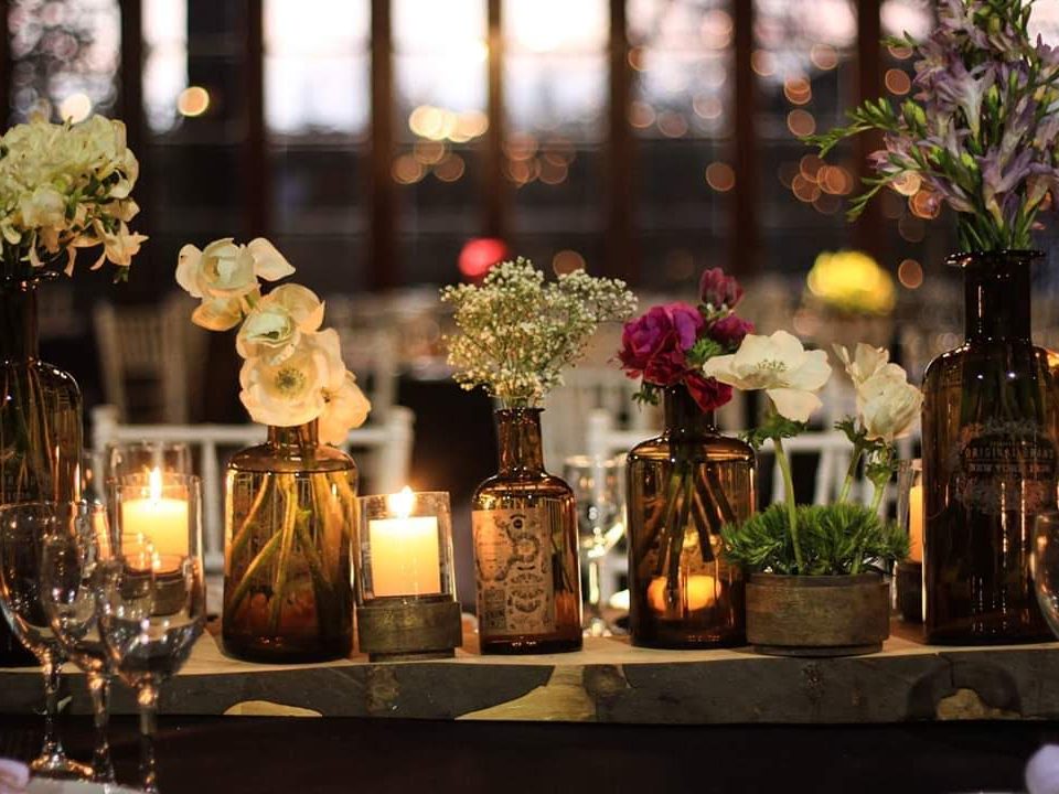 Centros de mesa con flores en frascos de vidrio y velas encendidas